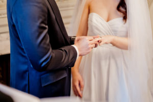 a close up image of the groom and bride exchanging rings