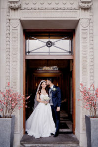 bride and groom inside the tall imposing doors of London's Marylebone Town Hall