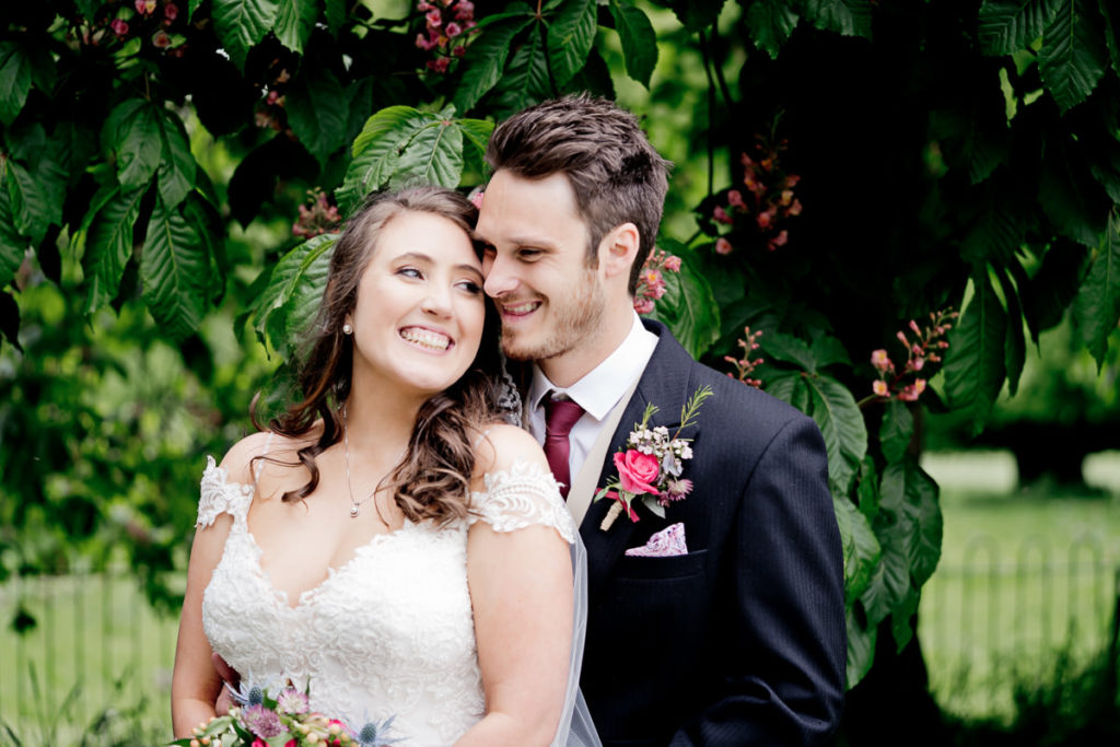 Happy bride and groom smiling together under a tree, as newly weds, at their Rowton Castle Wedding
