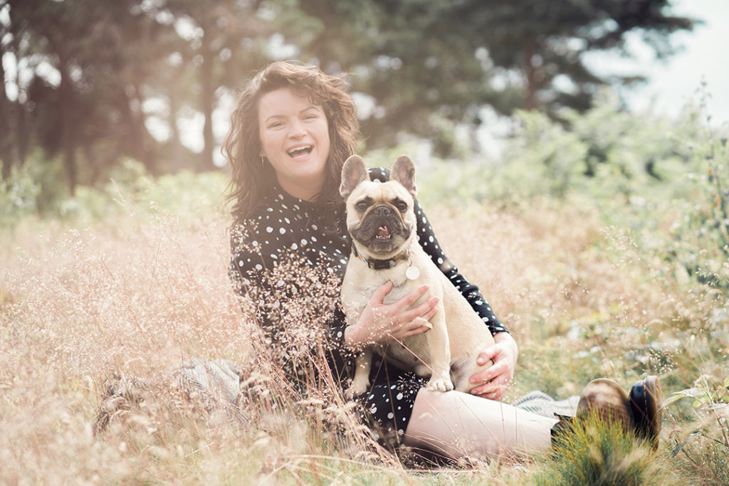laughing woman sat with a french bulldog