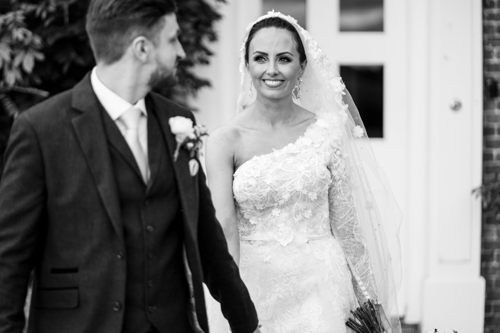 relaxed photo of bride as she is led by groom in black and white photo