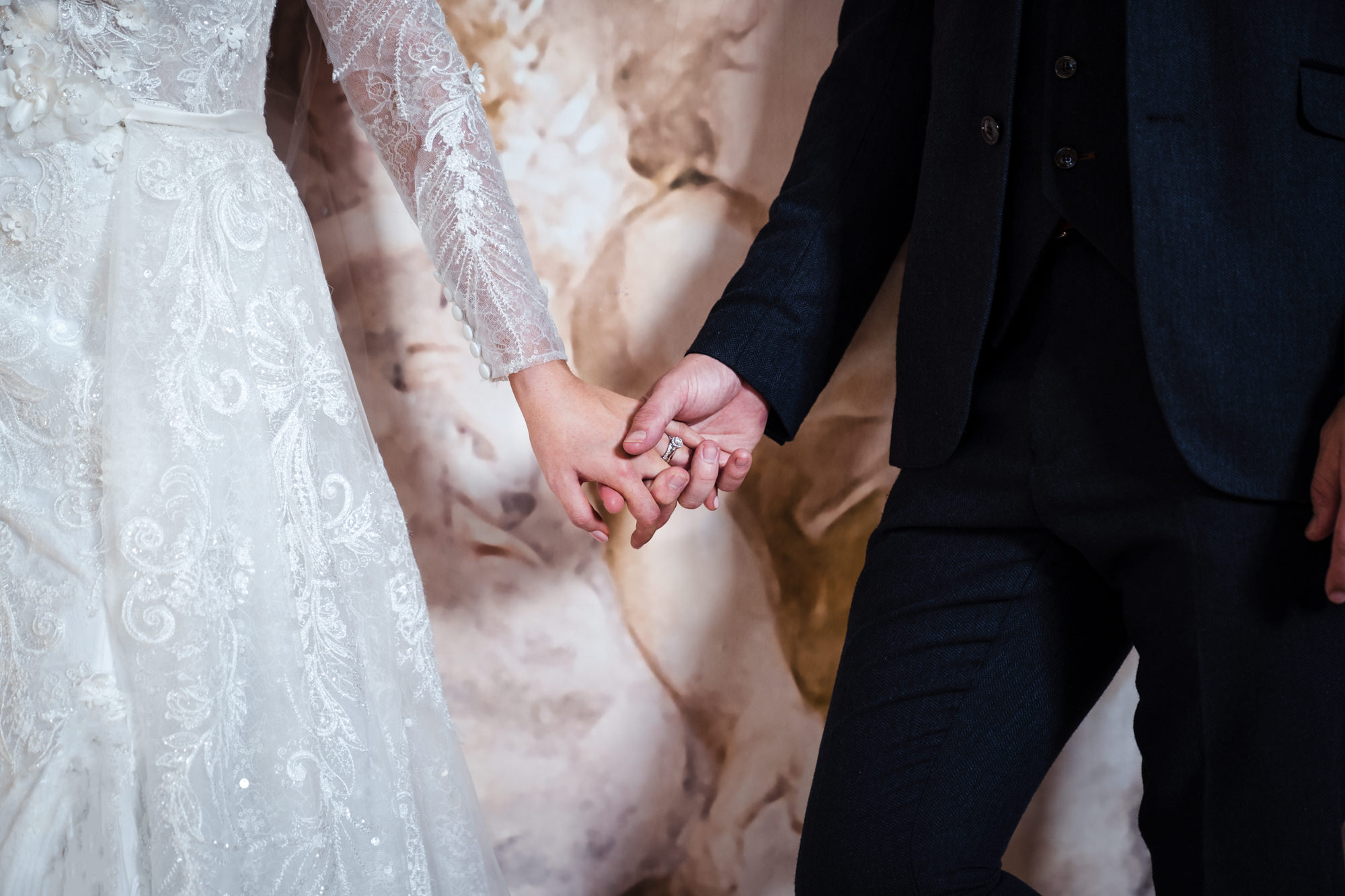 close up of bride and groom holding hands with a focus on the brides wedding ring