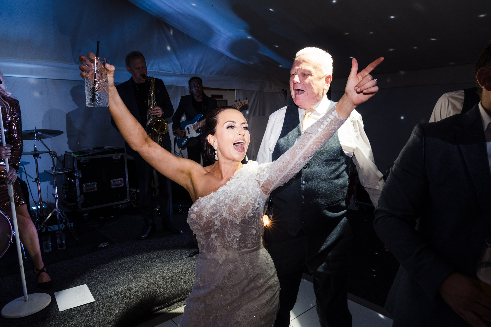 bride dances and throws arms in the air while dancing with her dad at her wedding