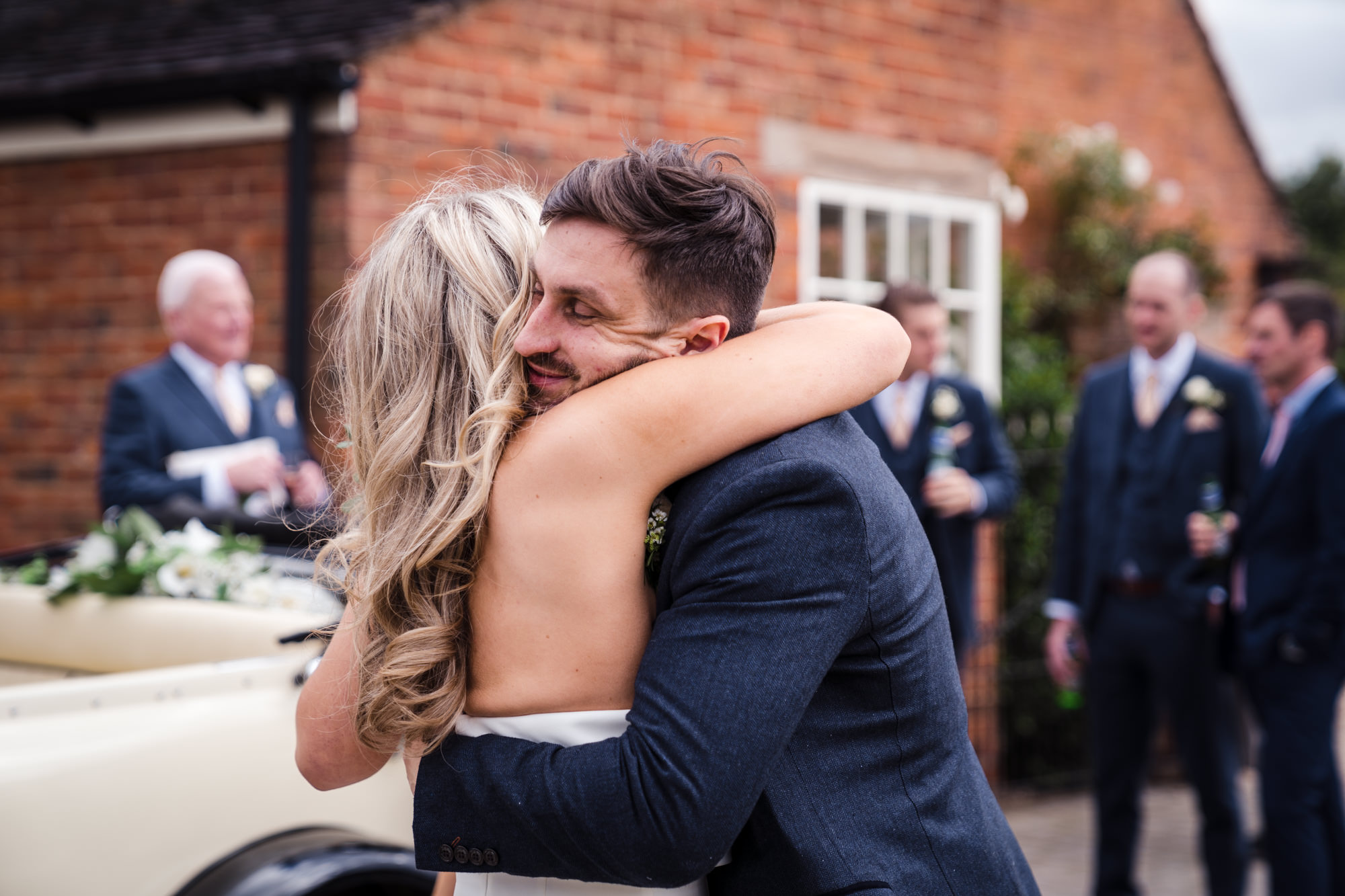 a smiling groom hugs a guest at his wedding reception