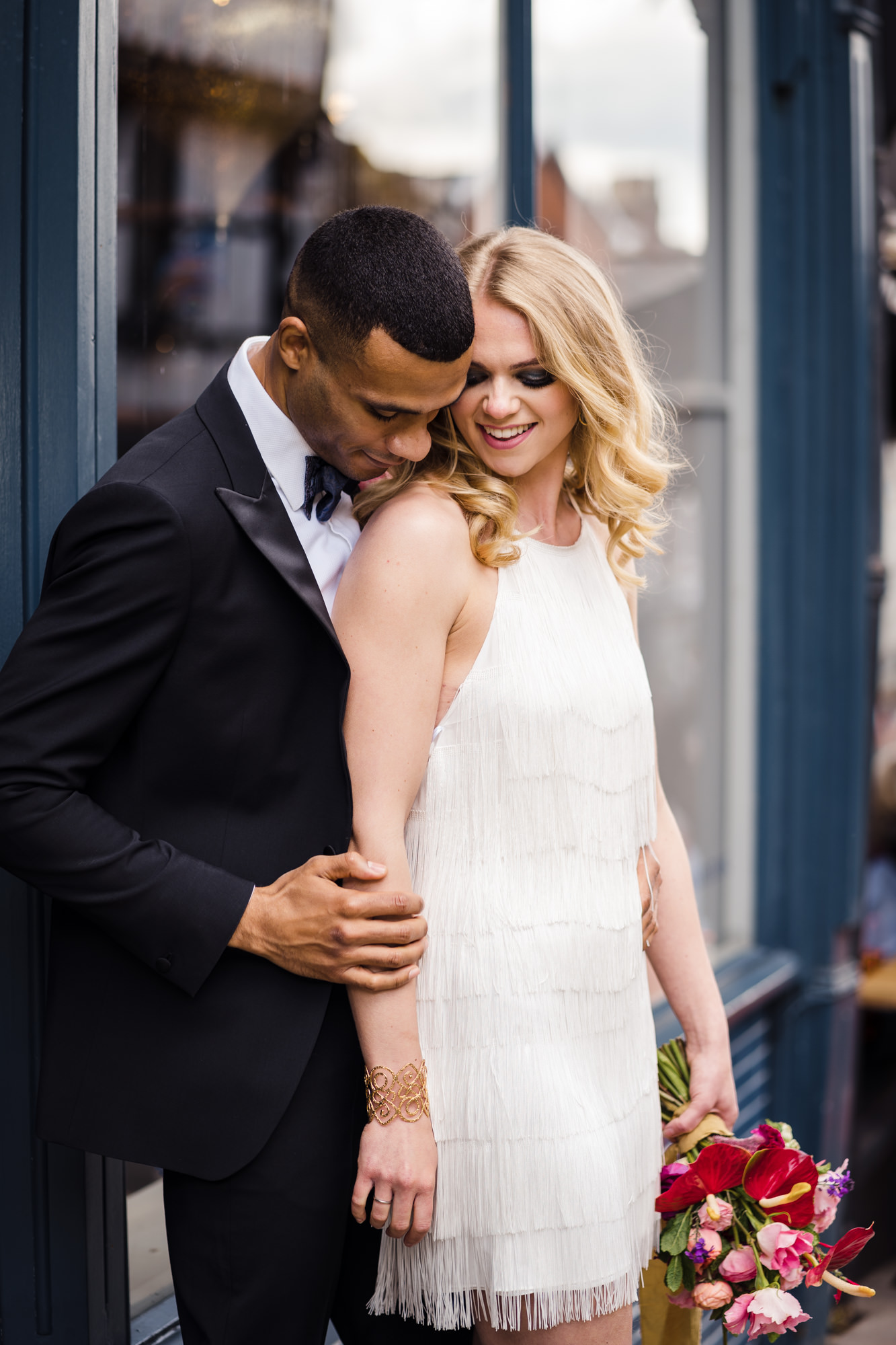 groom and bride embrace on a city street for wedding photos