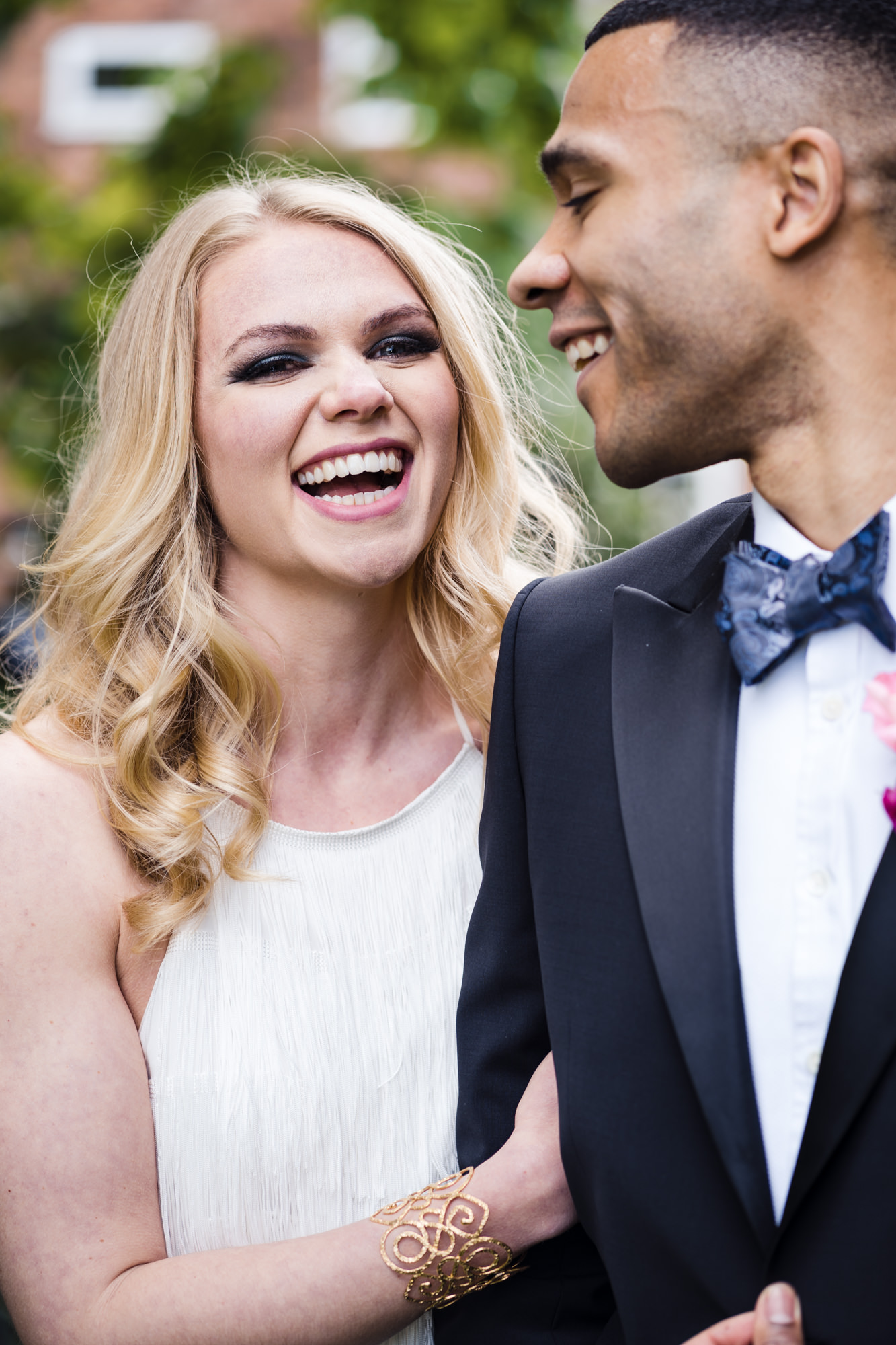 bride beams with laughter at the camera while groom looks back at her