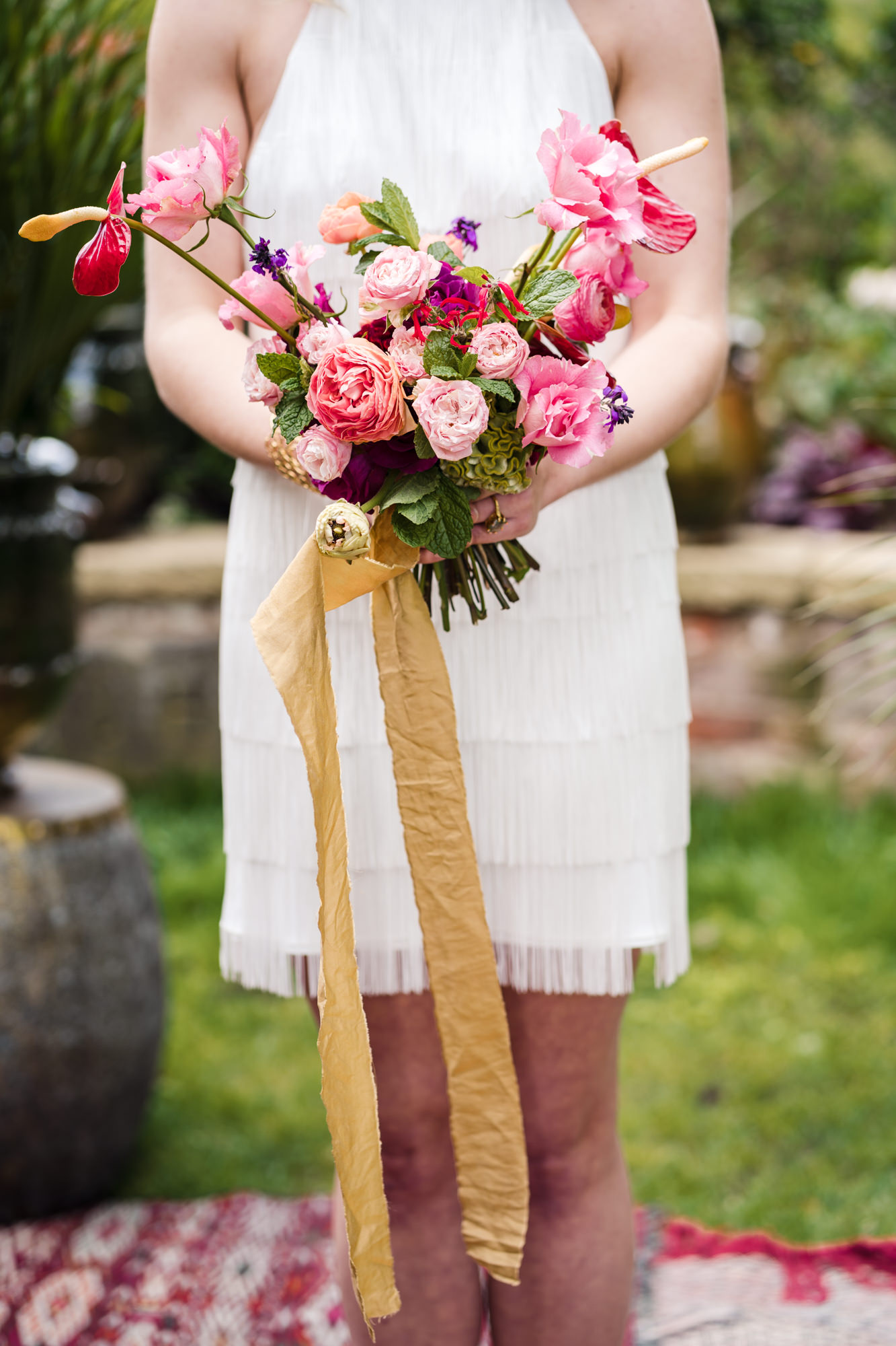close up of bride holding a pink and red colourful wedding bouquet from bloomin lupin