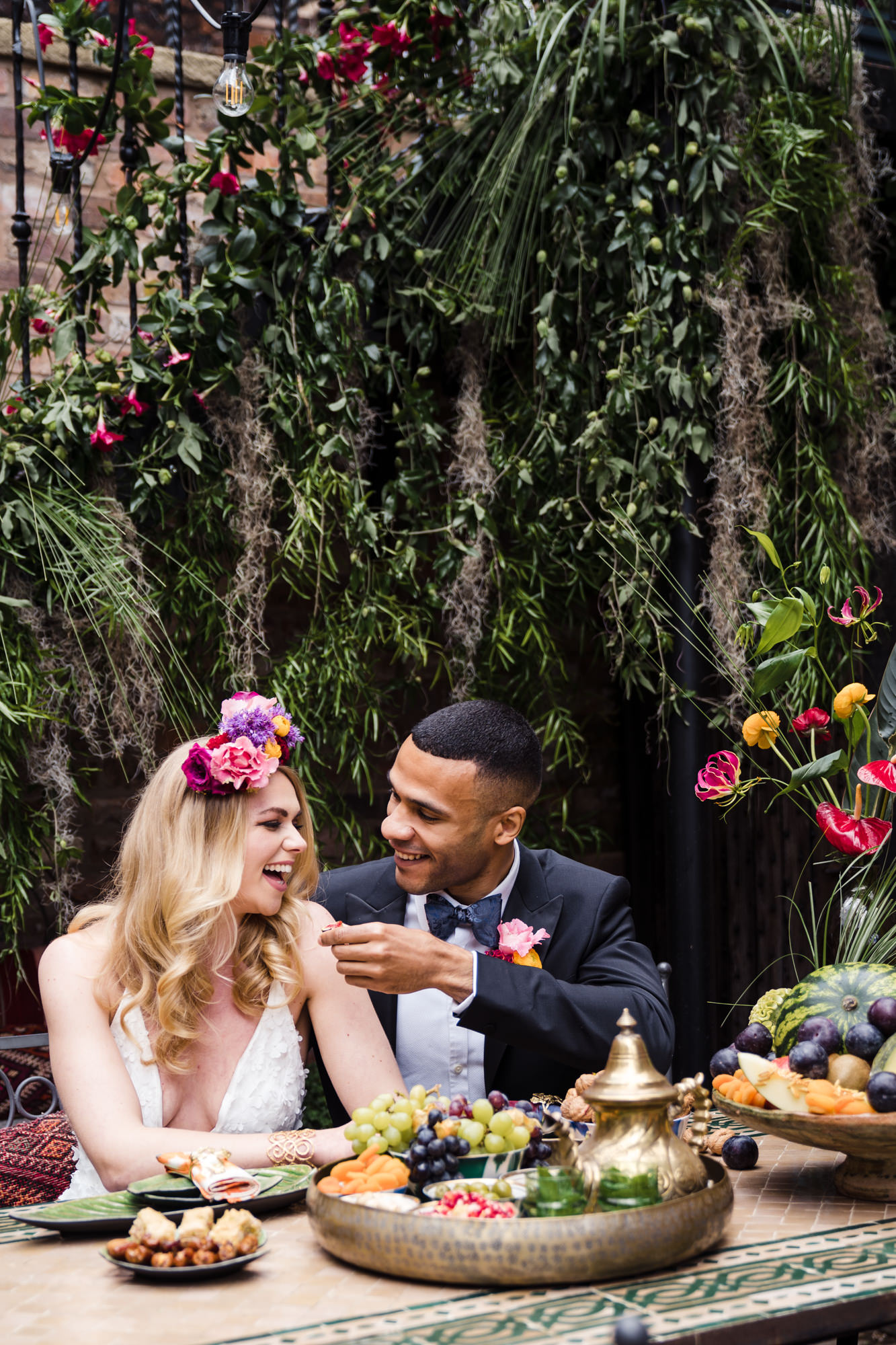 bride and groom feed each other fruit with a lush green leaf backdrop from bloomin lupin