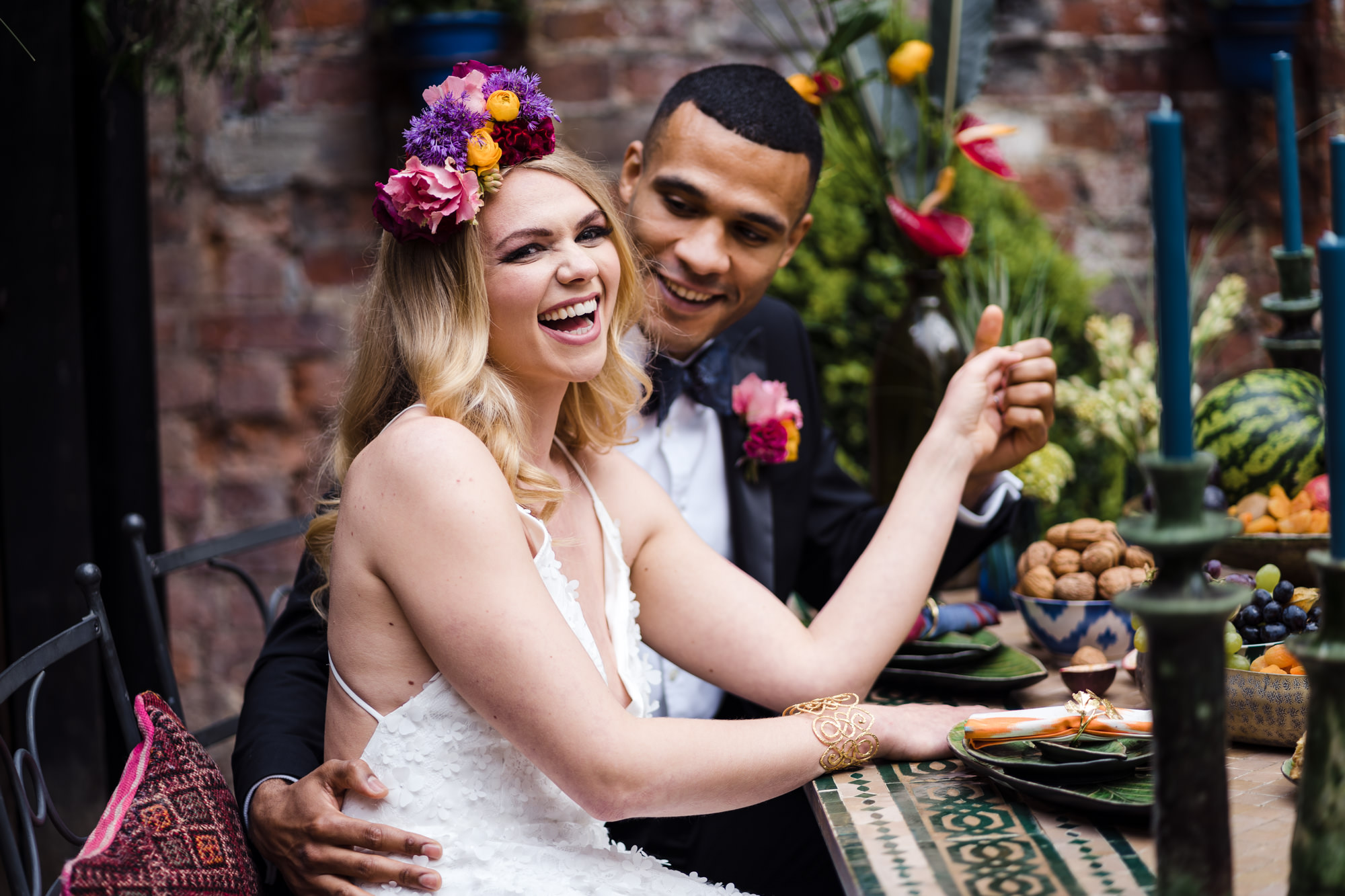 happy smiling bride with bold colourful head crown ad groom gazes at her