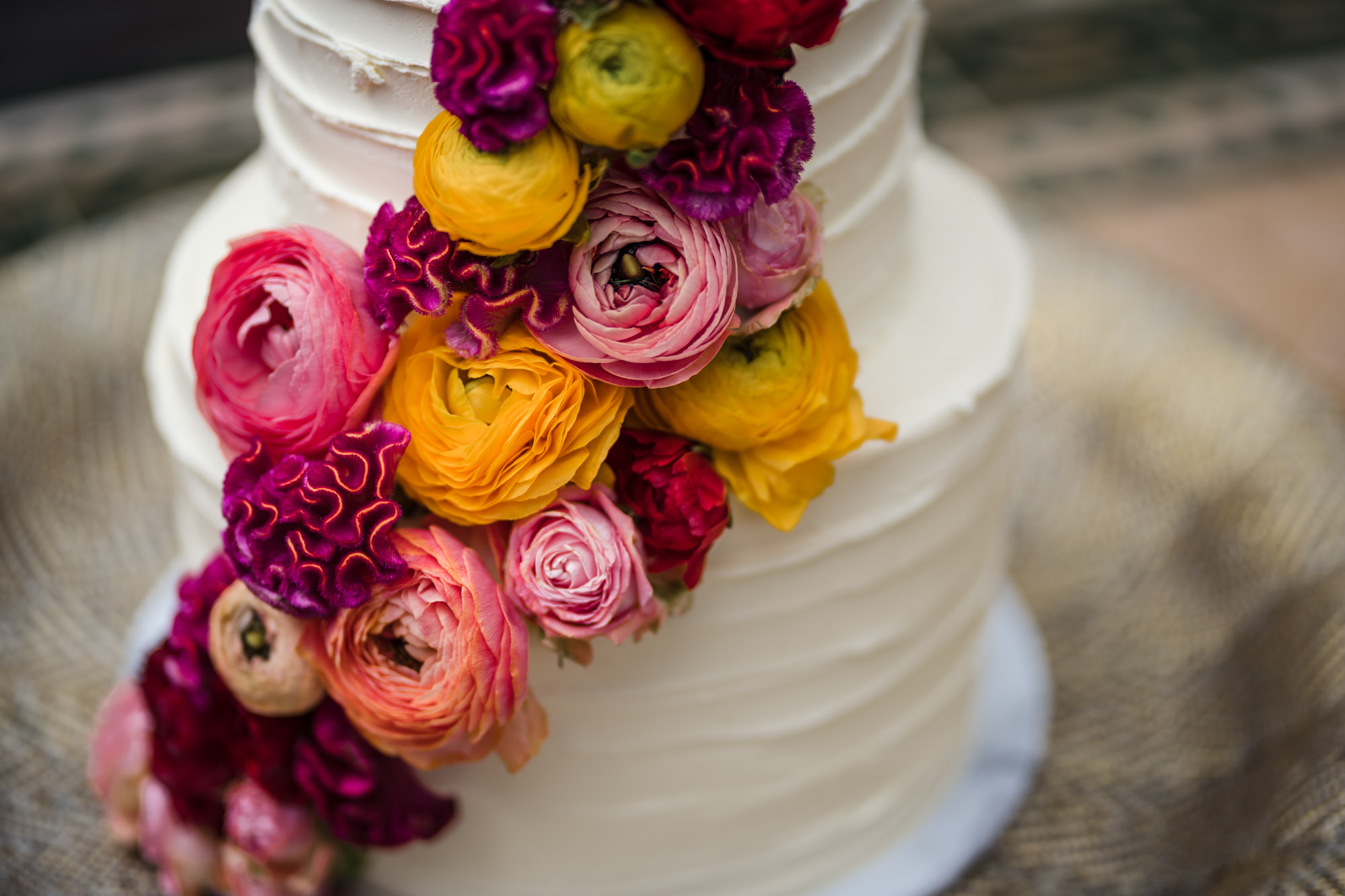 close up of statement bold colourful flowers on a white wedding cake
