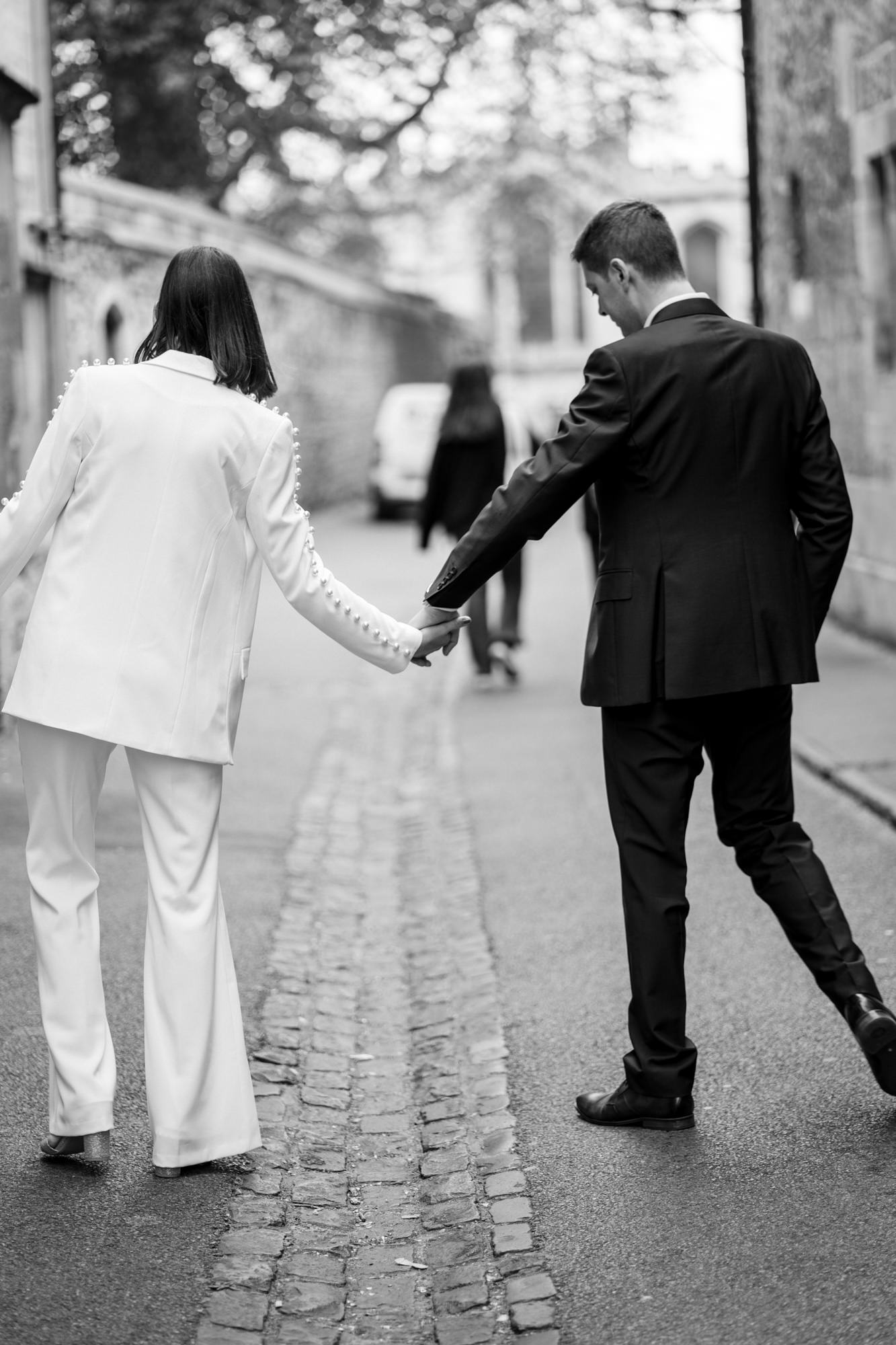 black and white photo of bride and groom walking hand in hand through oxford for their registry office city elopement