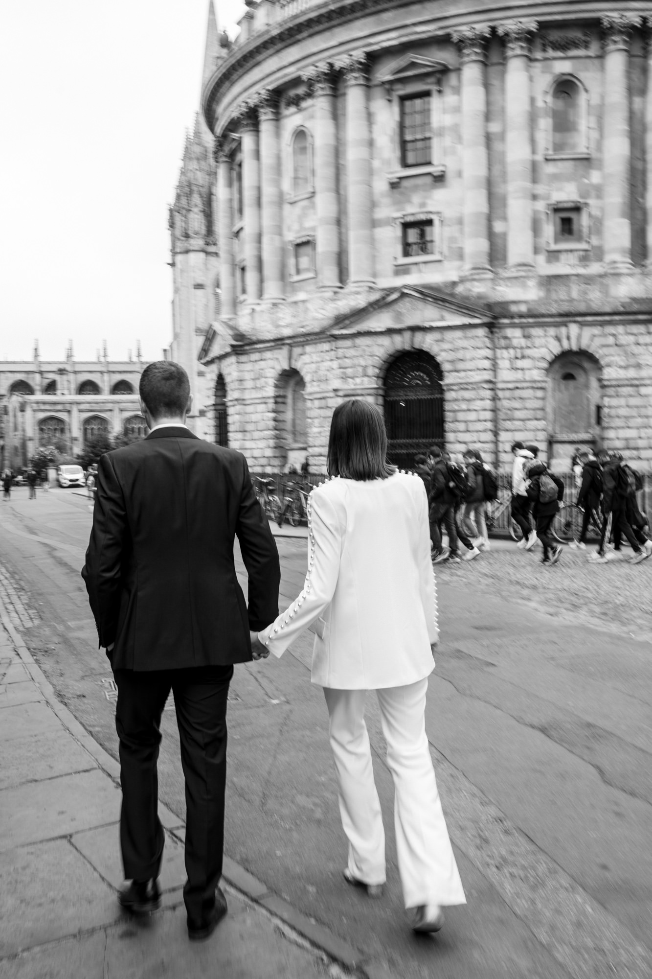 modern black and white couple photo from behind as they stroll through oxford city after their registry office elopement wedding