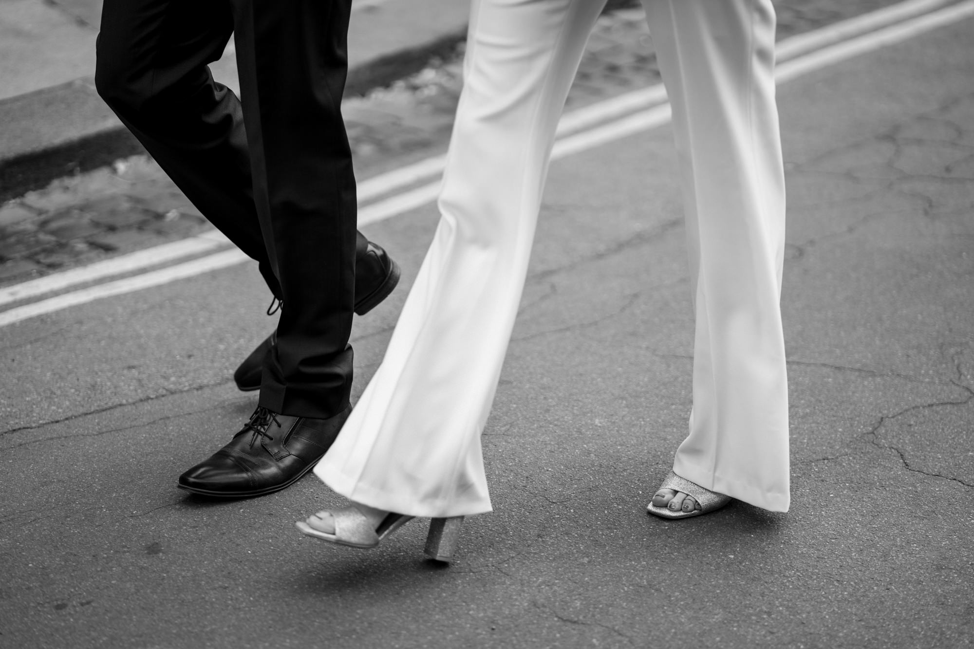 detail shot of bride and grooms feet as they walk showing off brides trousers from her bridal suit