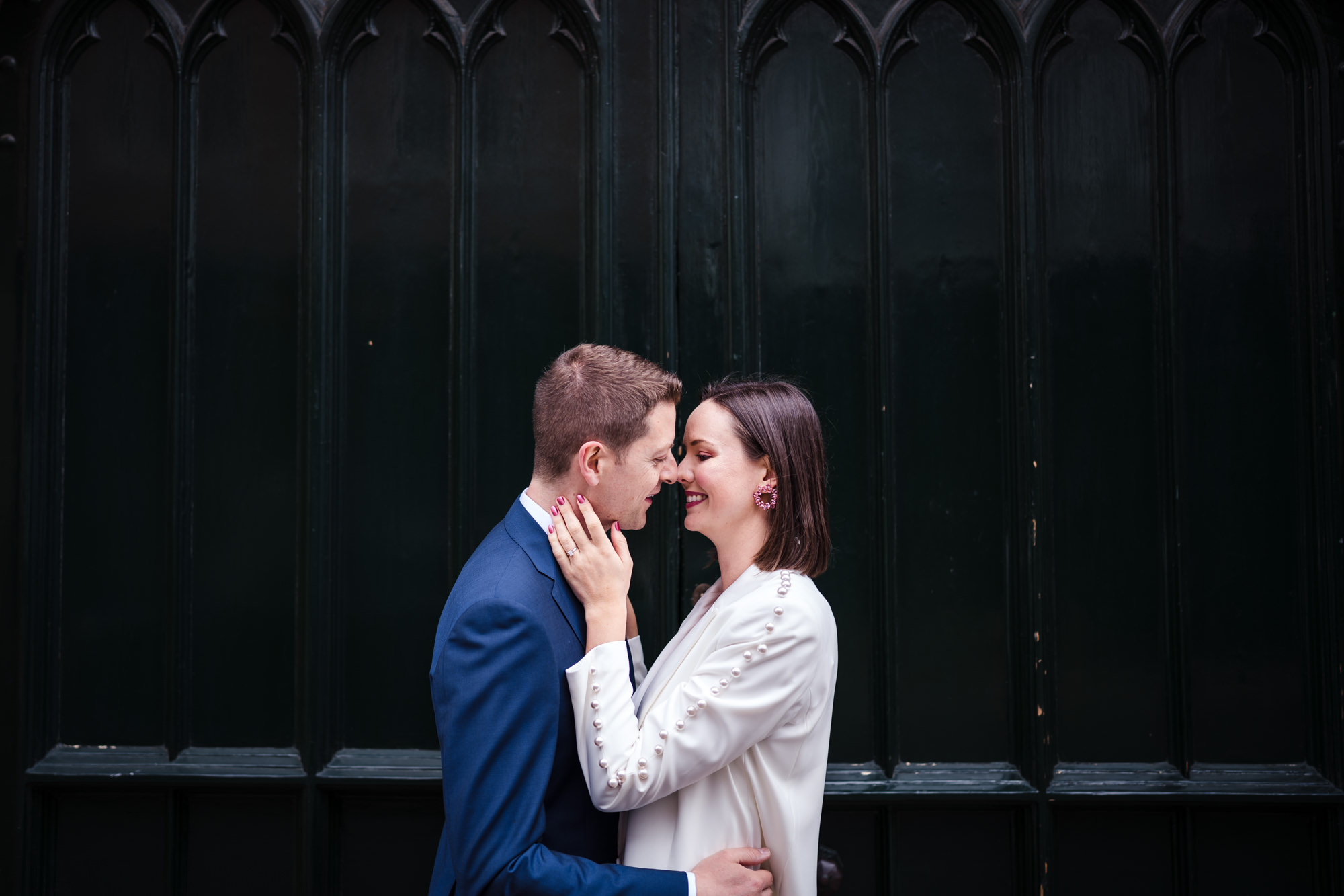 bride touches grooms face as they nearly kiss in oxford after their registry office wedding