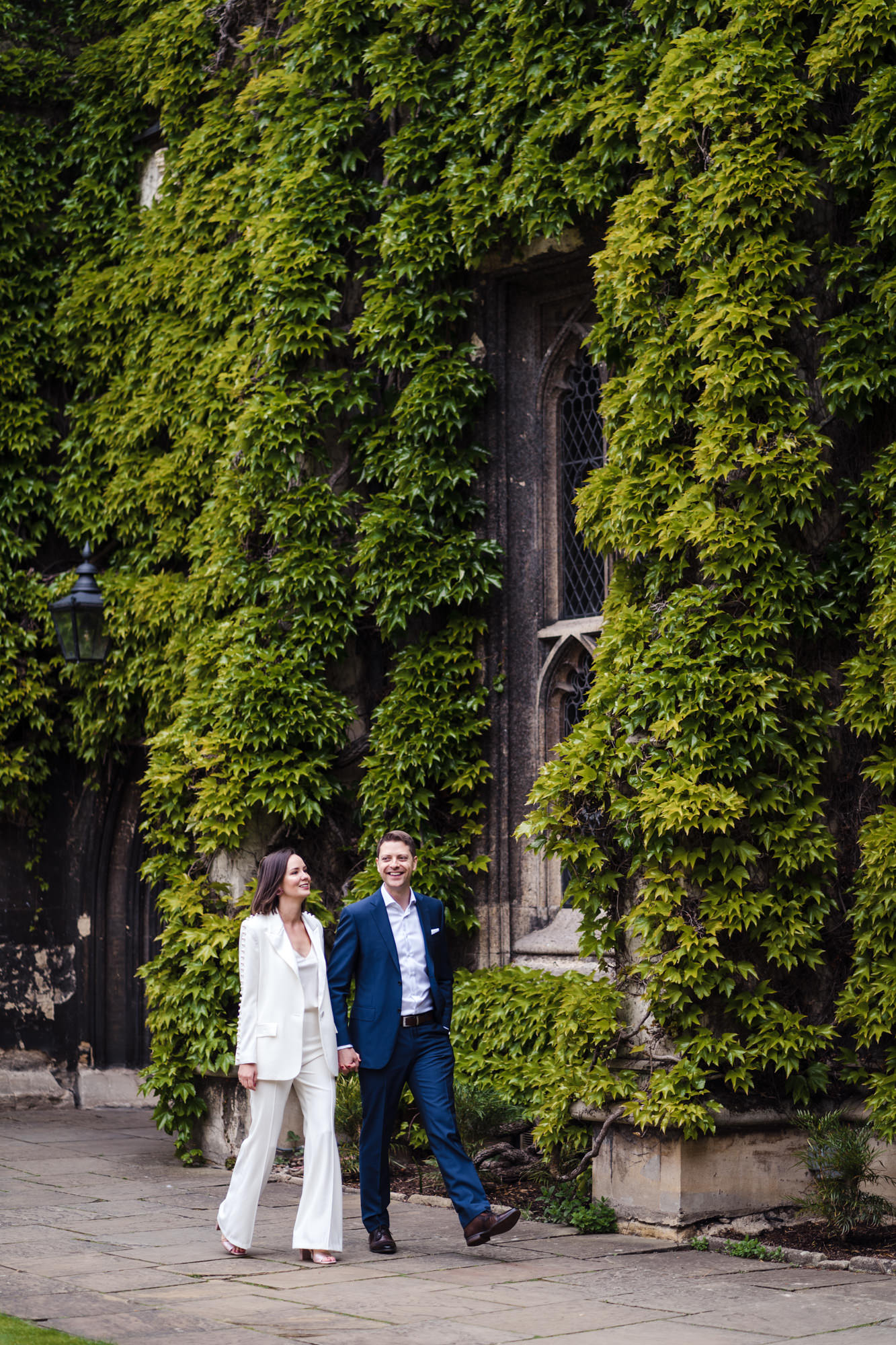 bride and groom look relaxed and happy as they stroll past ivy walls in oxford for their city elopement