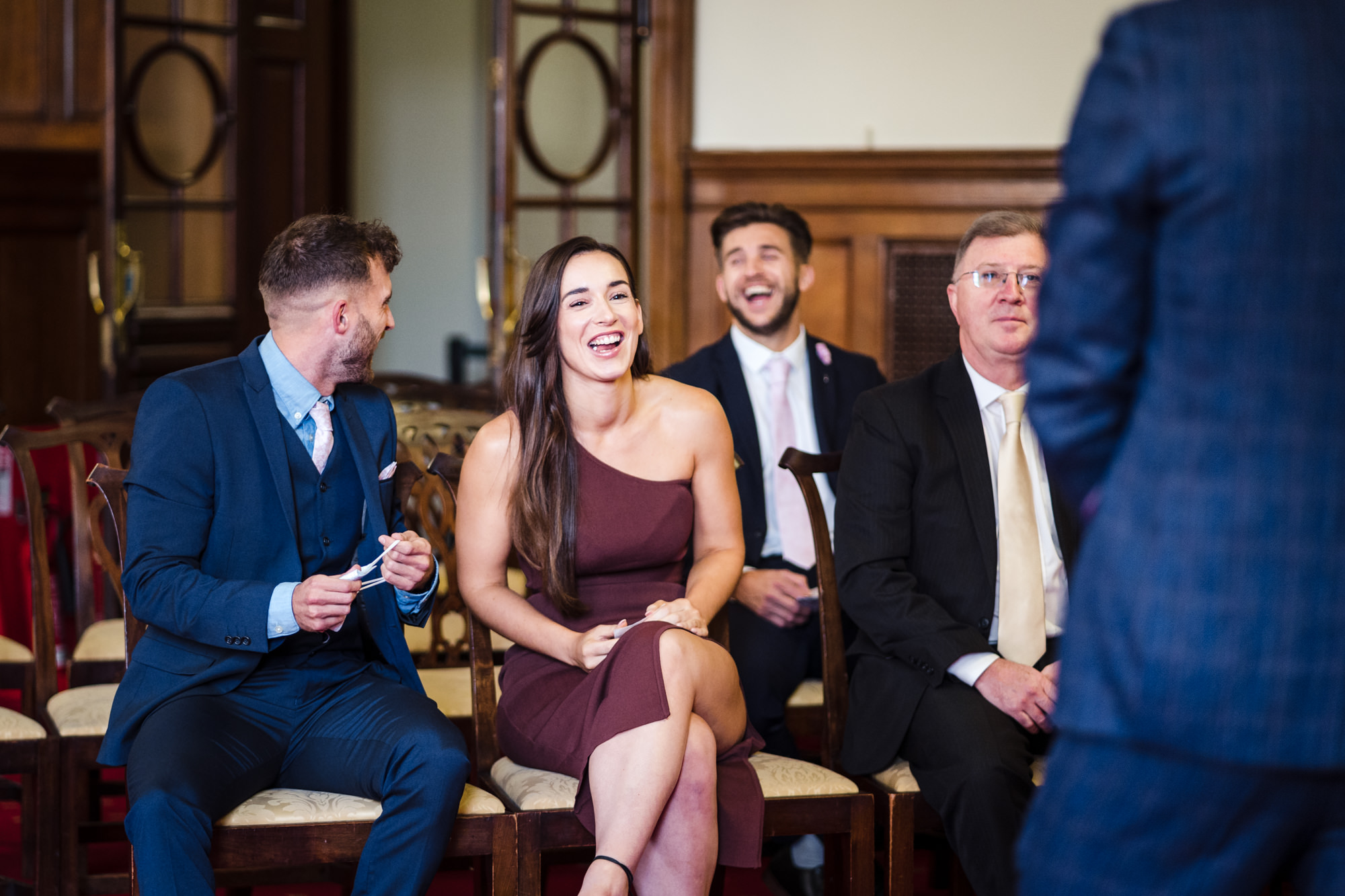 guests laugh and smile in the ceremony room at bath guildhall waiting for the arrival of the bride
