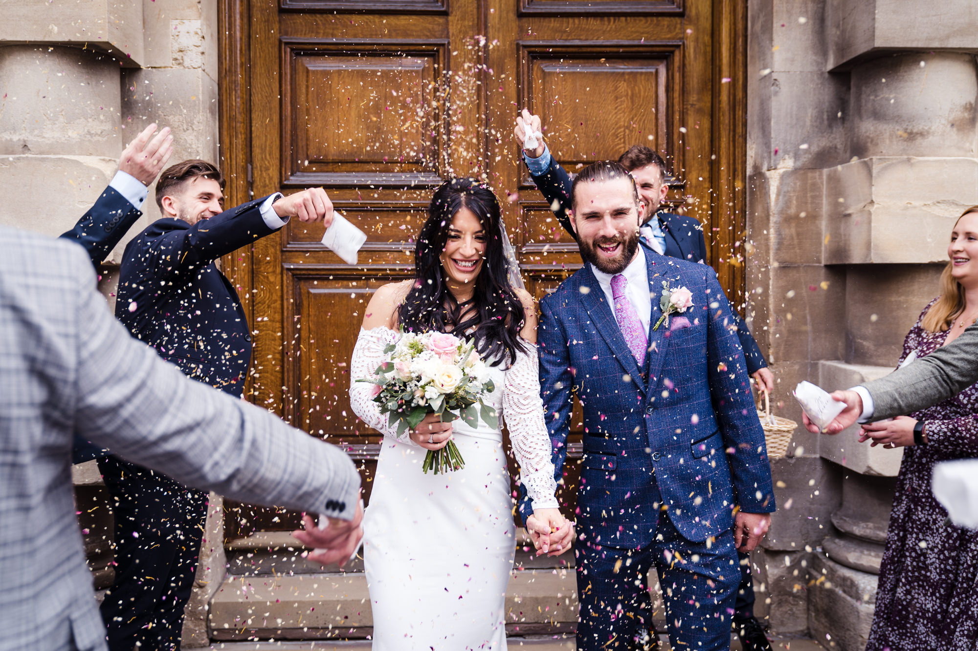 bride and groom walk through confetti smiling in bath city