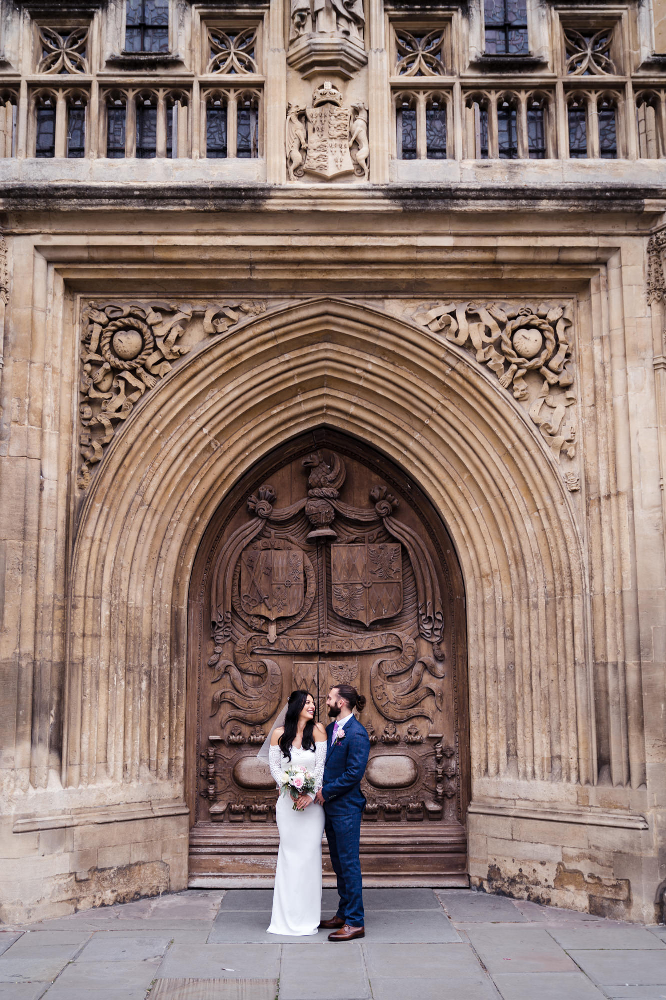 newly married bride and groom stand for couple portrait in front of the grand bath abbey doors