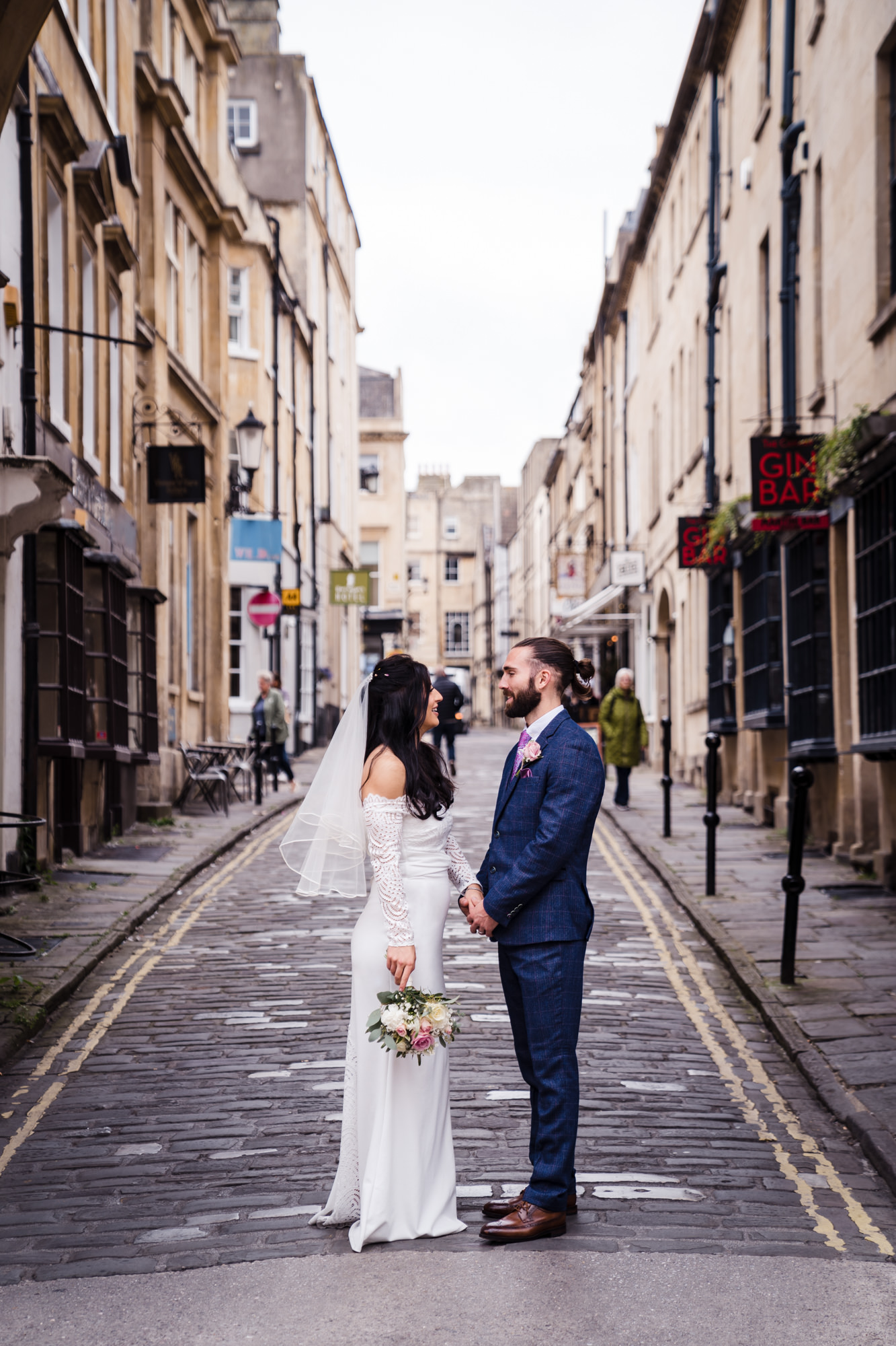 street modern photo of couple on wedding day surrounded by city shops on cobbled street