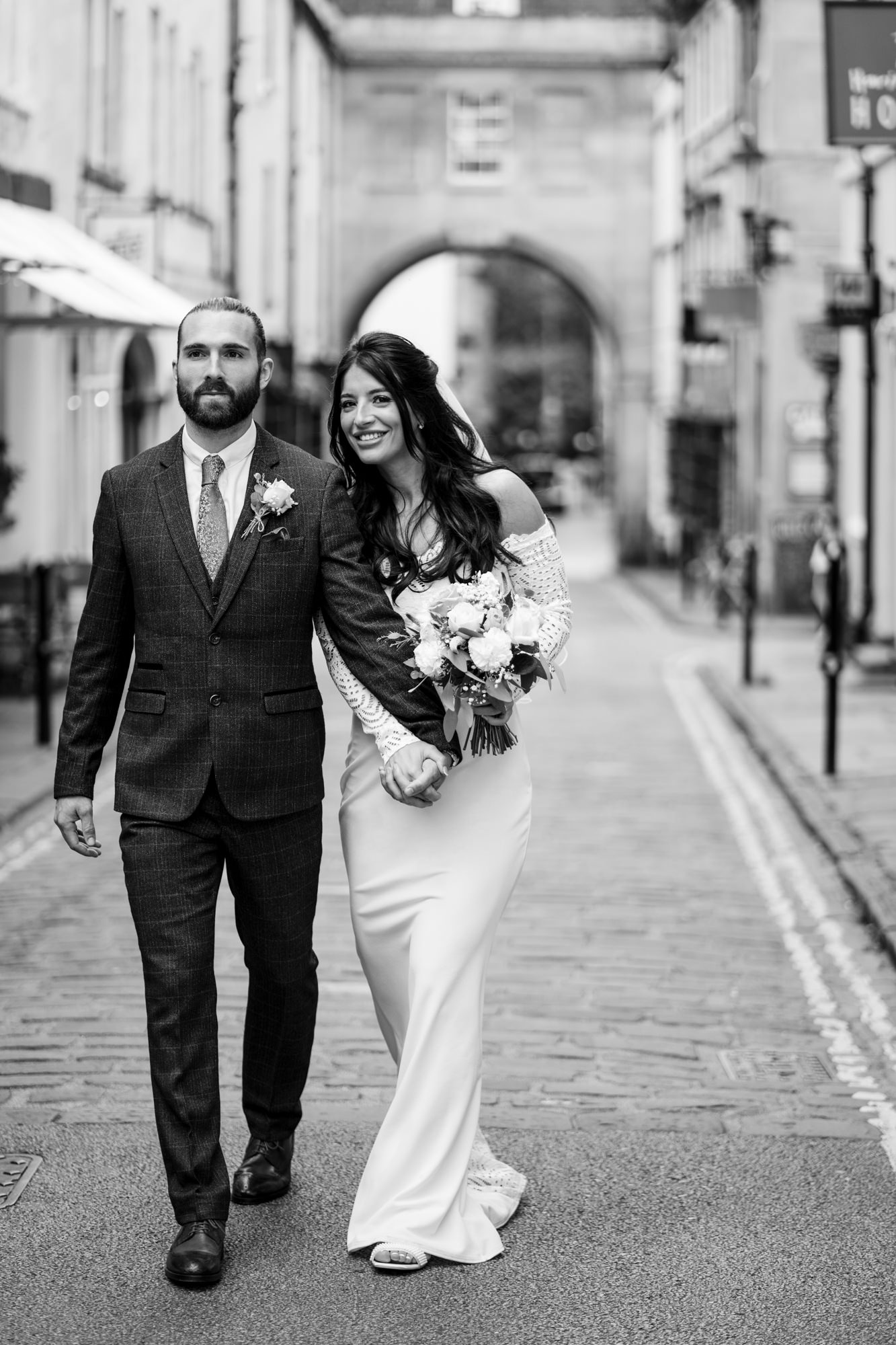 black and white photo of couple walking holding hands through city during their intimate small wedding