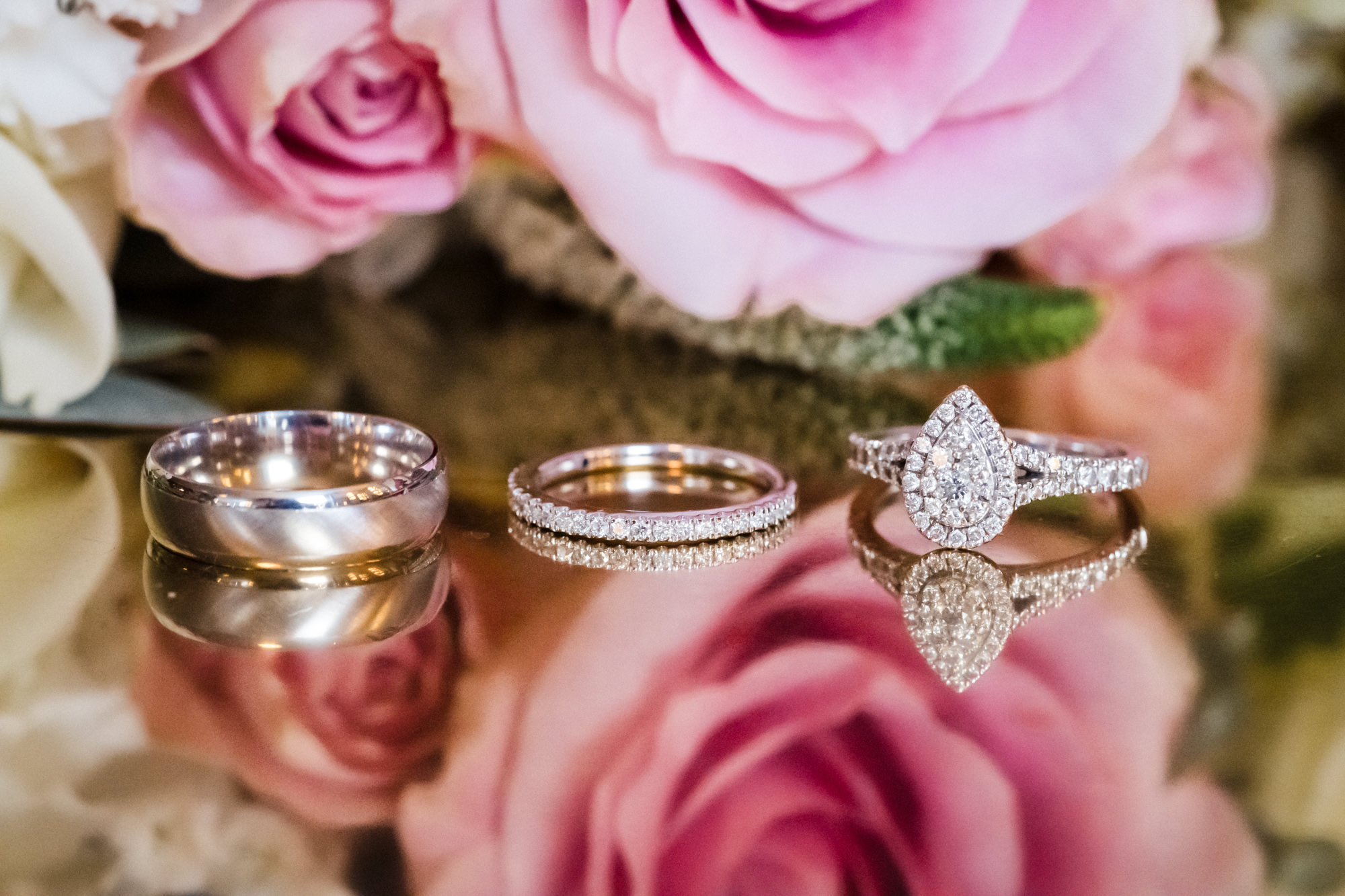 macro reflective photo of wedding rings using flowers as backdrop