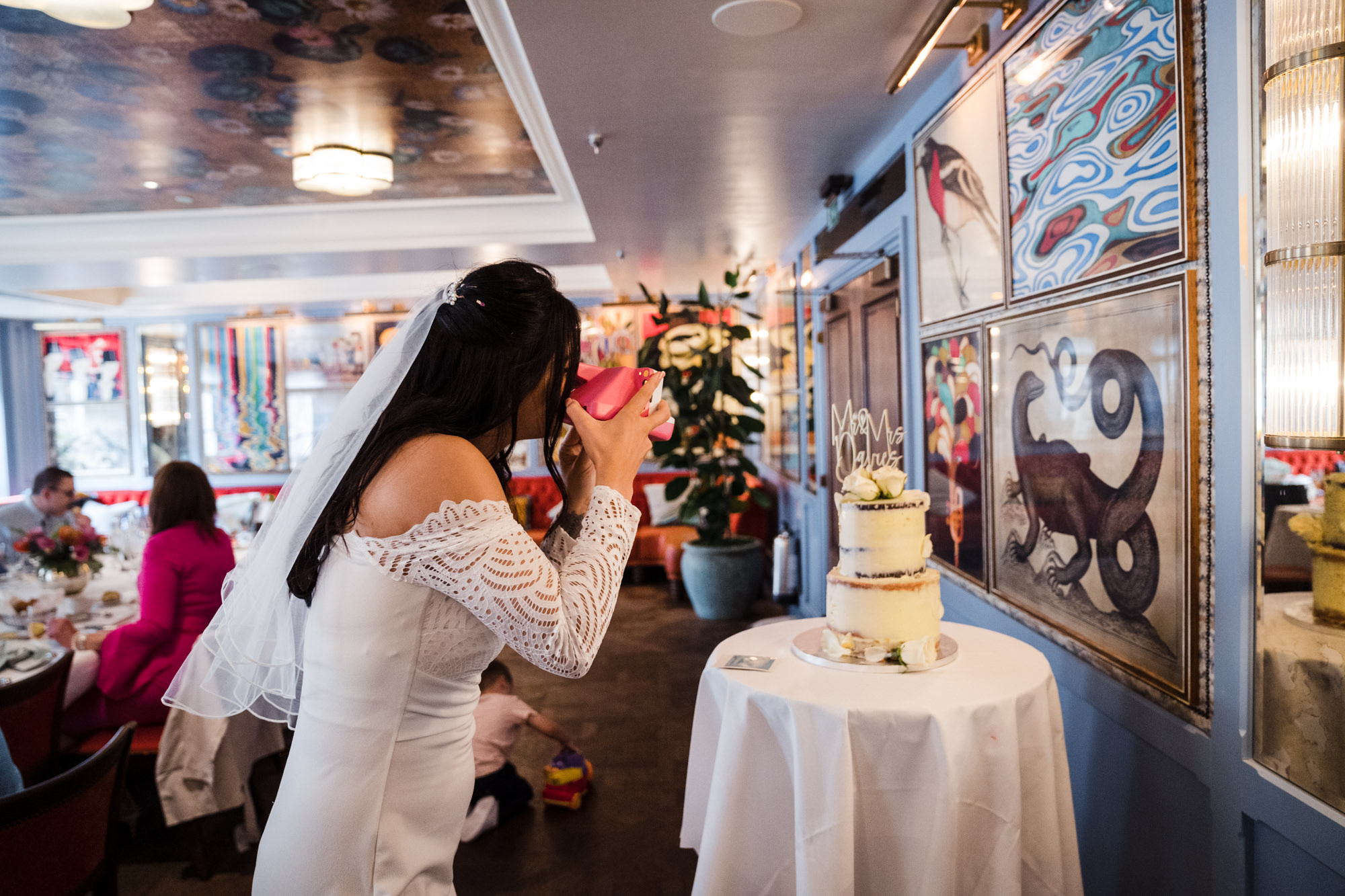 bride takes a Polaroid photo of the wedding cake