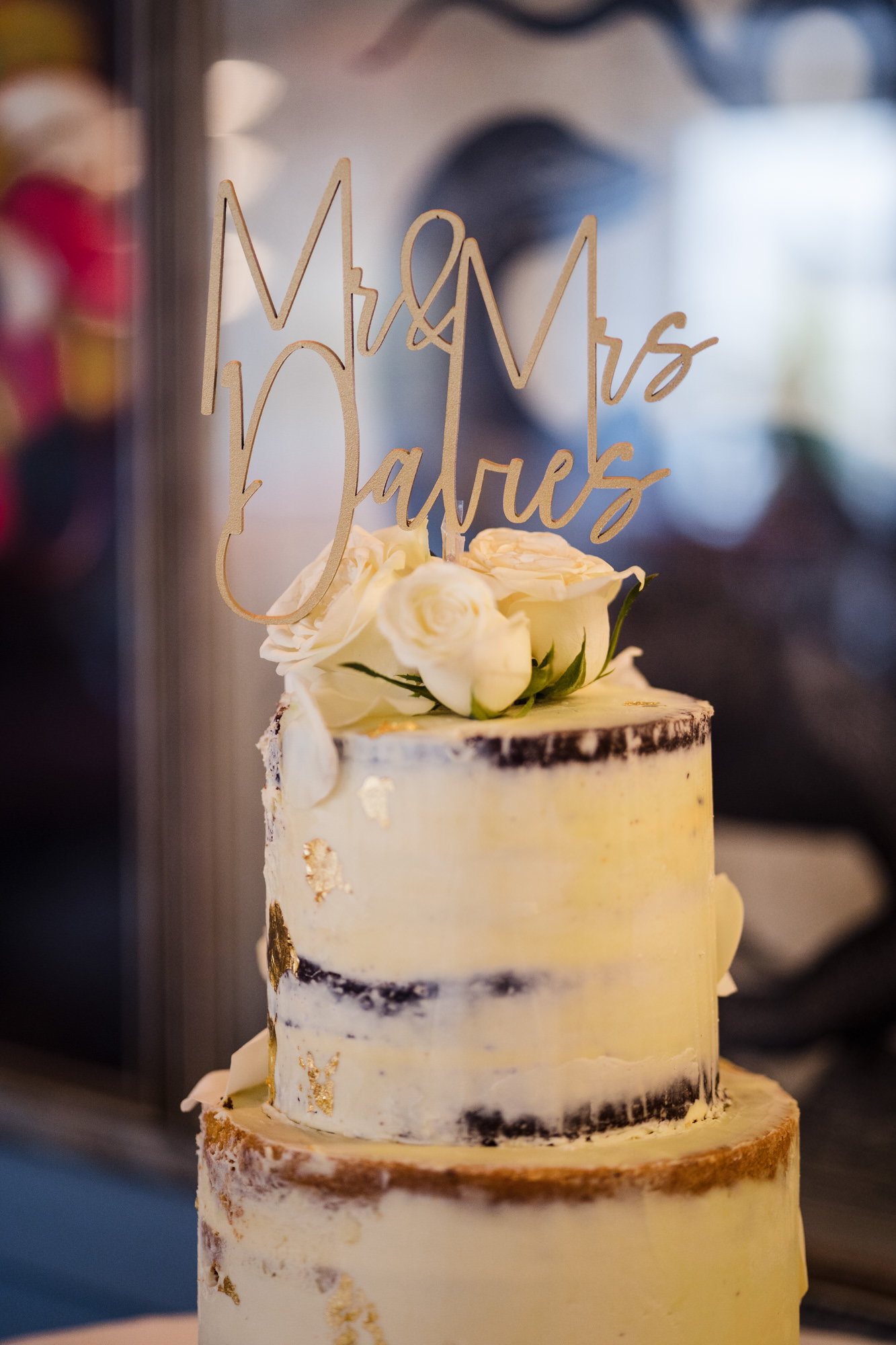 close up of naked iced wedding cake with big gold letters of wedding couples name