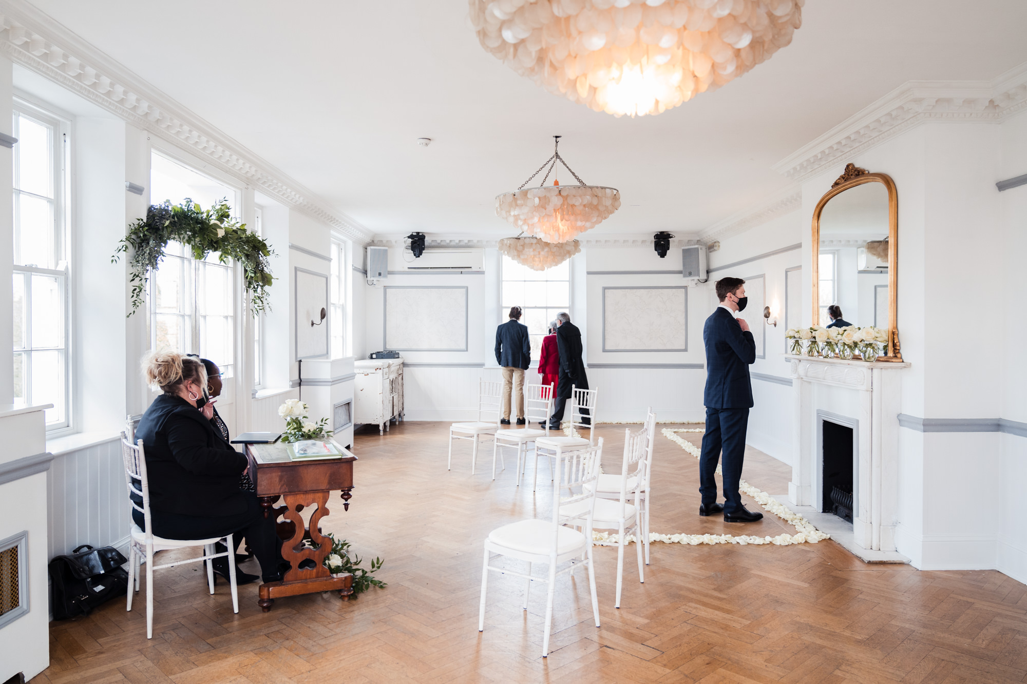 wide photograph showing white ceremony room at belair house with floral detail on the floor making a pathway