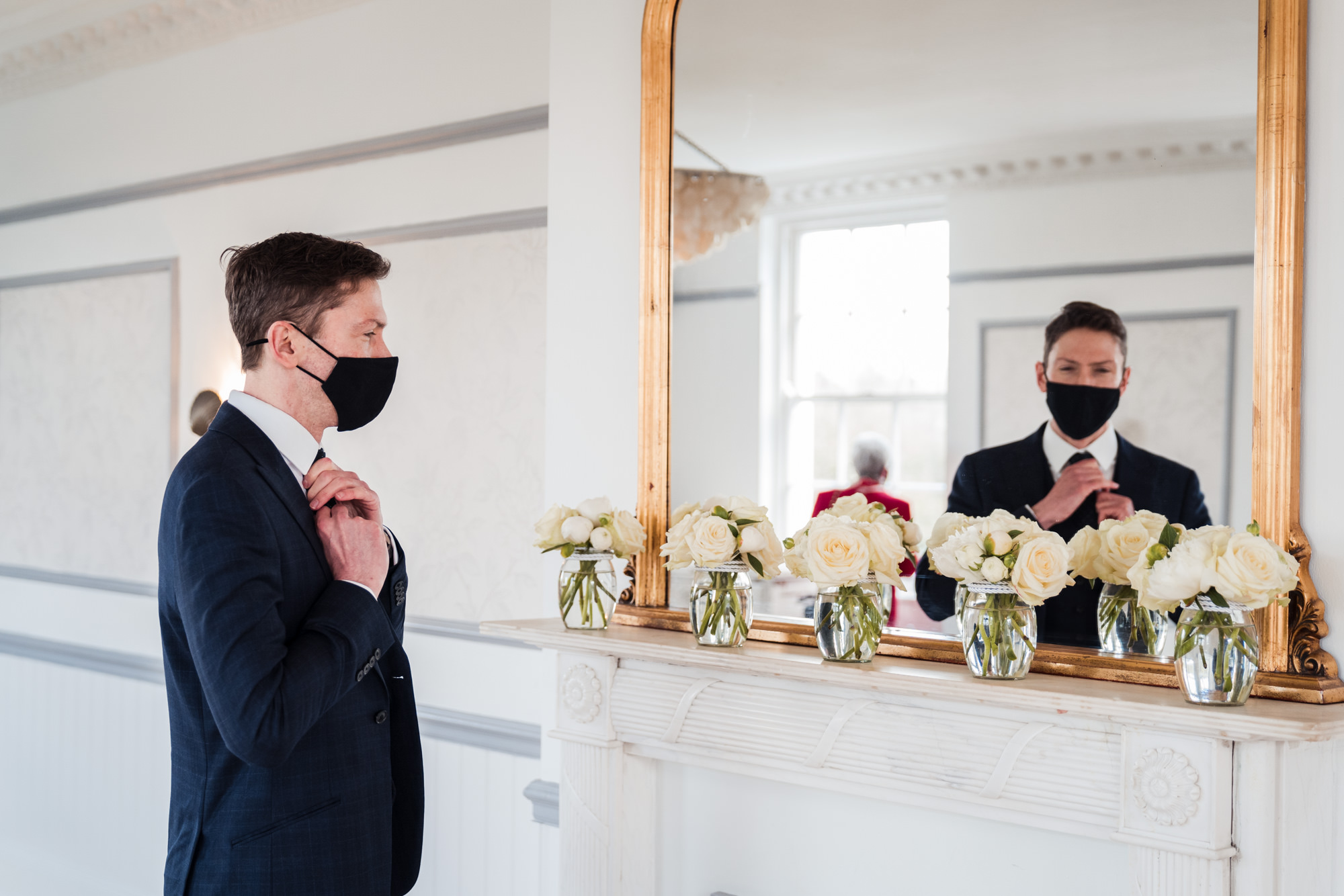 photograph of groom looking in the mirror adjusting his tie