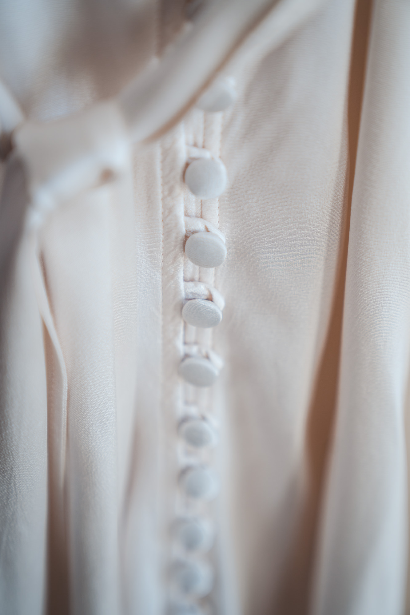 close up photo of buttons on bride's wedding dress