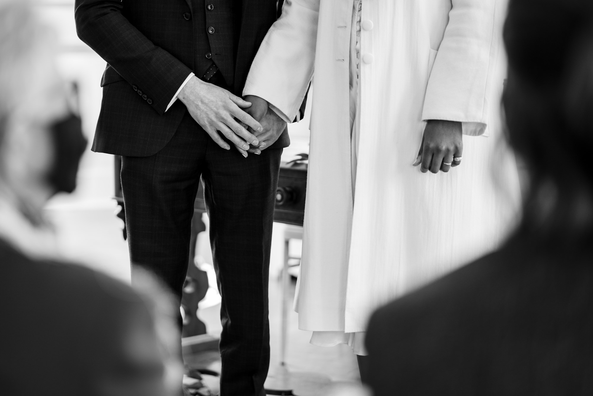 black and white photo of bride and groom holding hands during the wedding ceremony