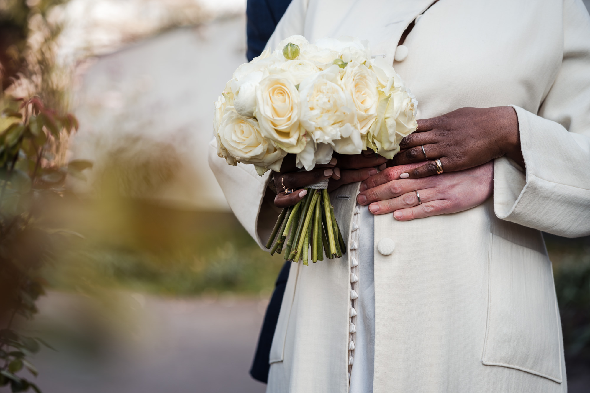 close up photo of bride's bouquet and both hands showing off their rings
