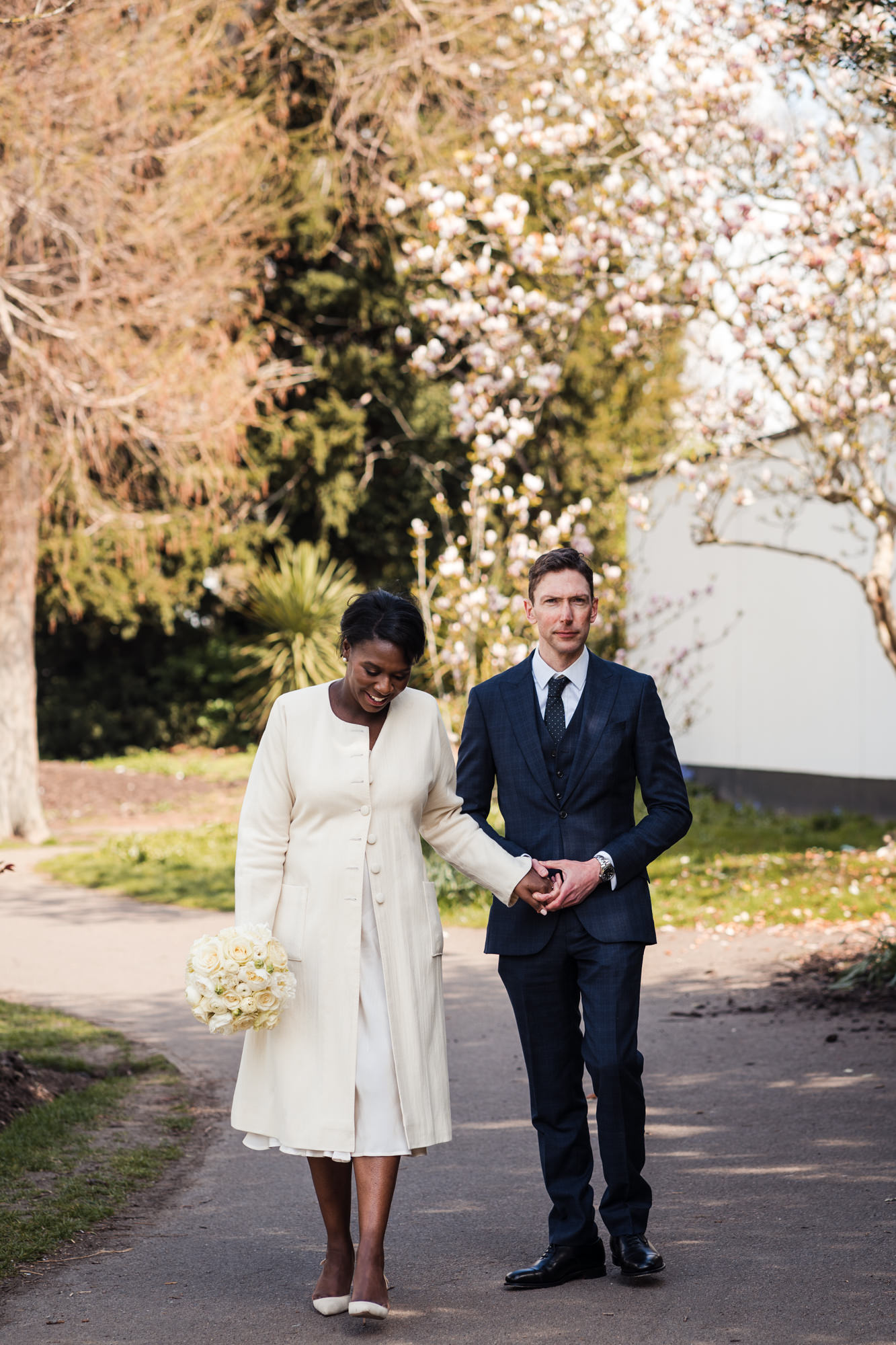 bride and groom holding hands and strolling through a south london park looking content and relaxed