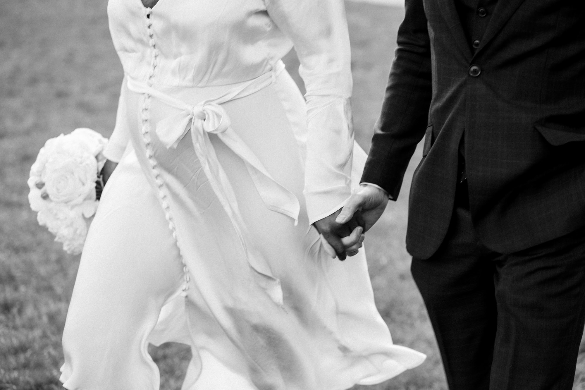 black and white modern portrait of bride and groom holding hands
