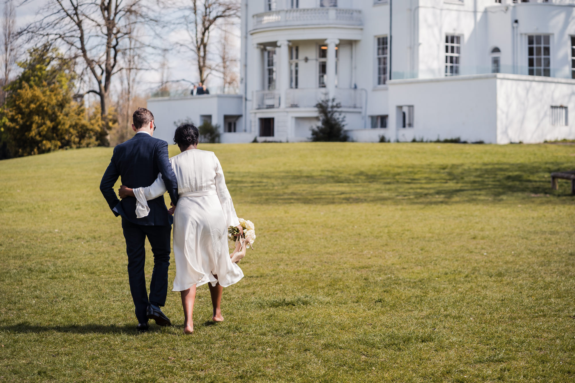 bride and groom walk arm in arm through a park towards their wedding venue in south london