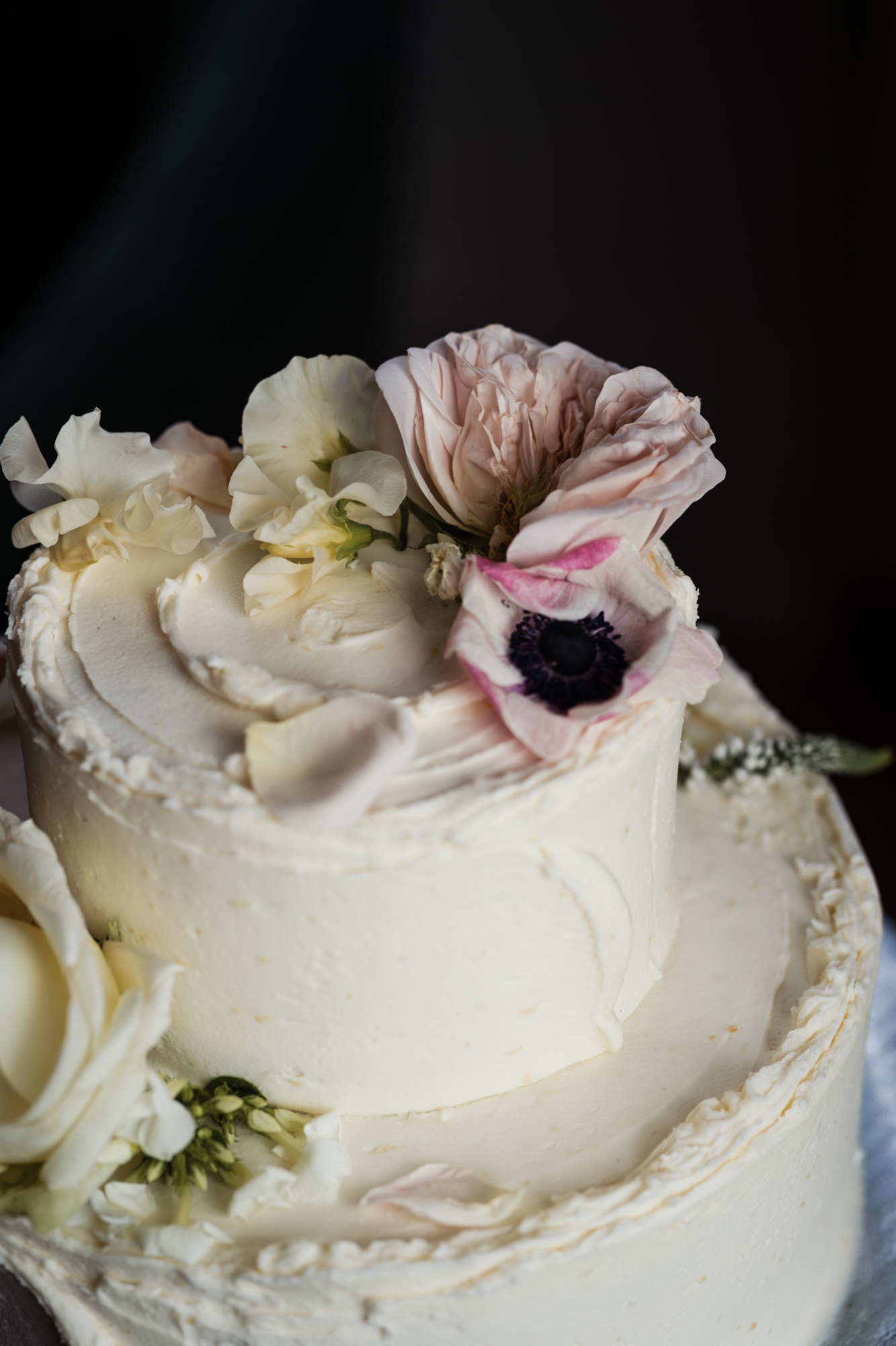 close up of pink flower on top of two tier white wedding cake from london's Violet Cakes By Claire Ptak