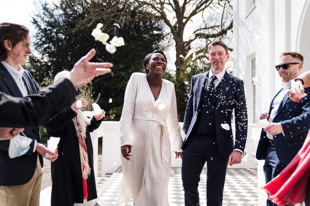 bride and groom walk through real white petal confetti