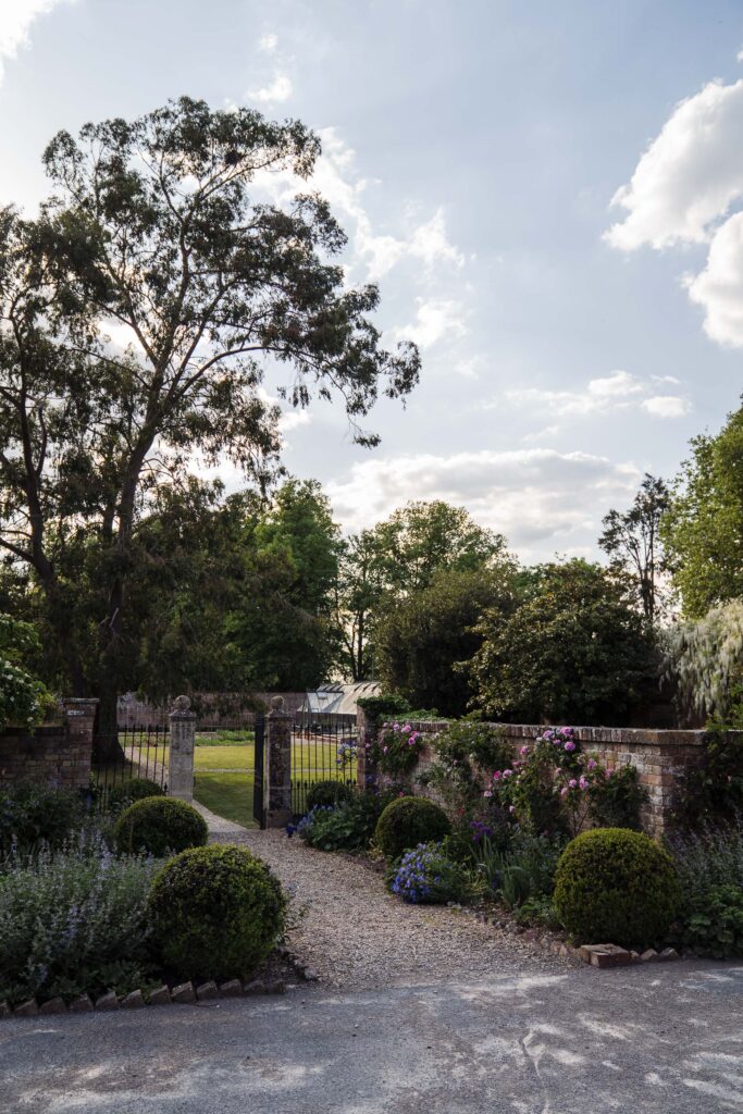 Garden path and gate at Elmore Court with trees and wild planting