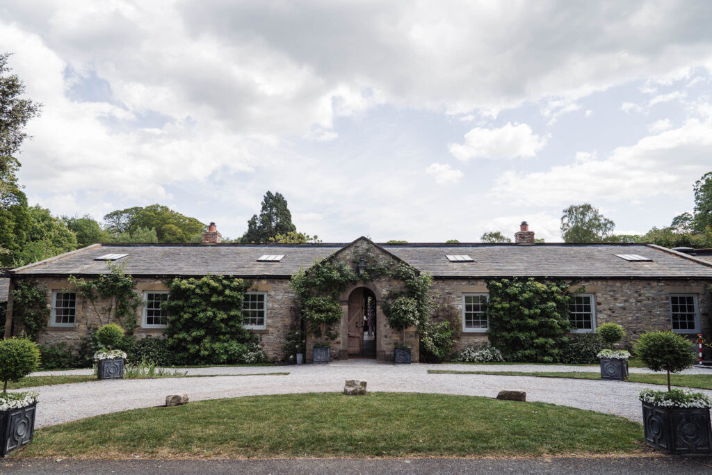 Middleton Lodge orangery exterior with ivy-covered stone walls and arched entrance, set around the courtyard lawn.